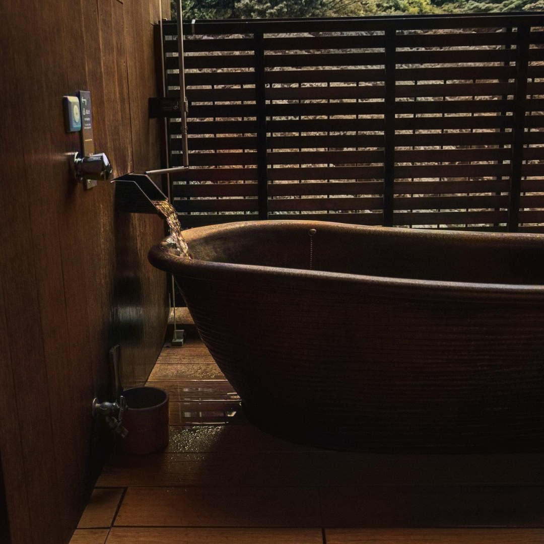 A peaceful, rustic wooden bathtub being filled with water in an outdoor setting, perfect for a calming self-care routine or mindfulness practice. Ideal for relaxation and stress relief, promoting mental wellness and tranquility.
